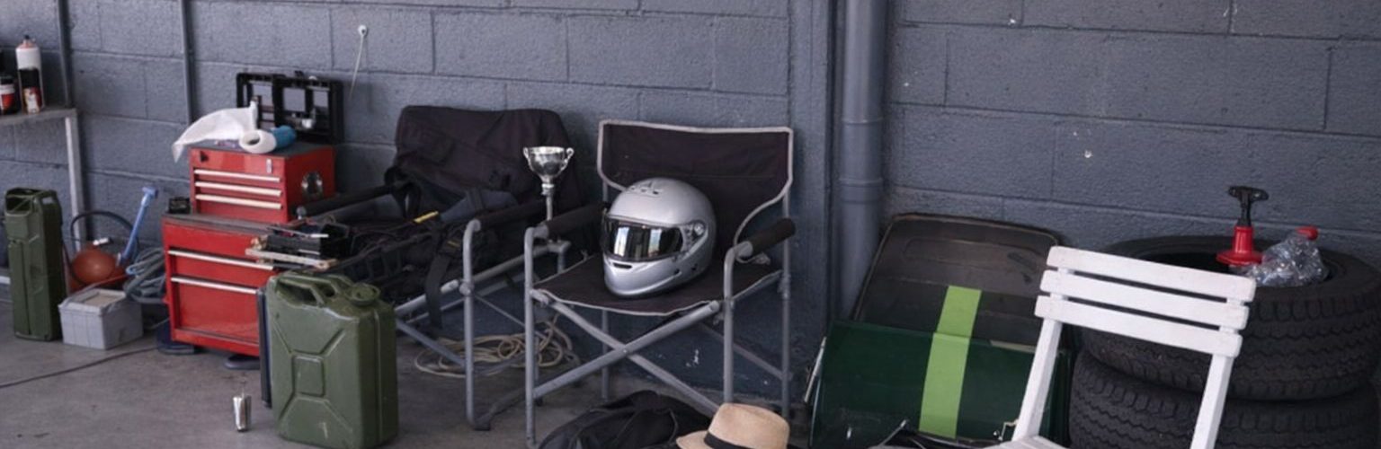 Träningsutrustning och motorsportstillbehör packade i ett garage för transport.