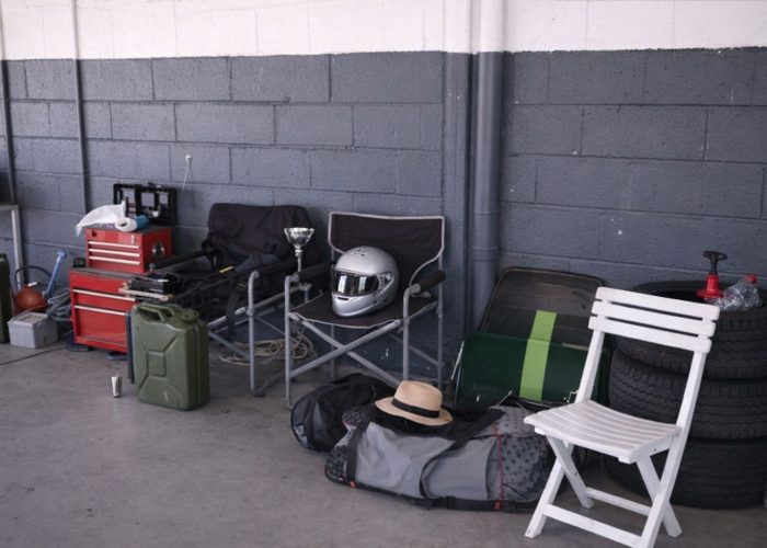 Träningsutrustning och motorsportstillbehör packade i ett garage för transport.