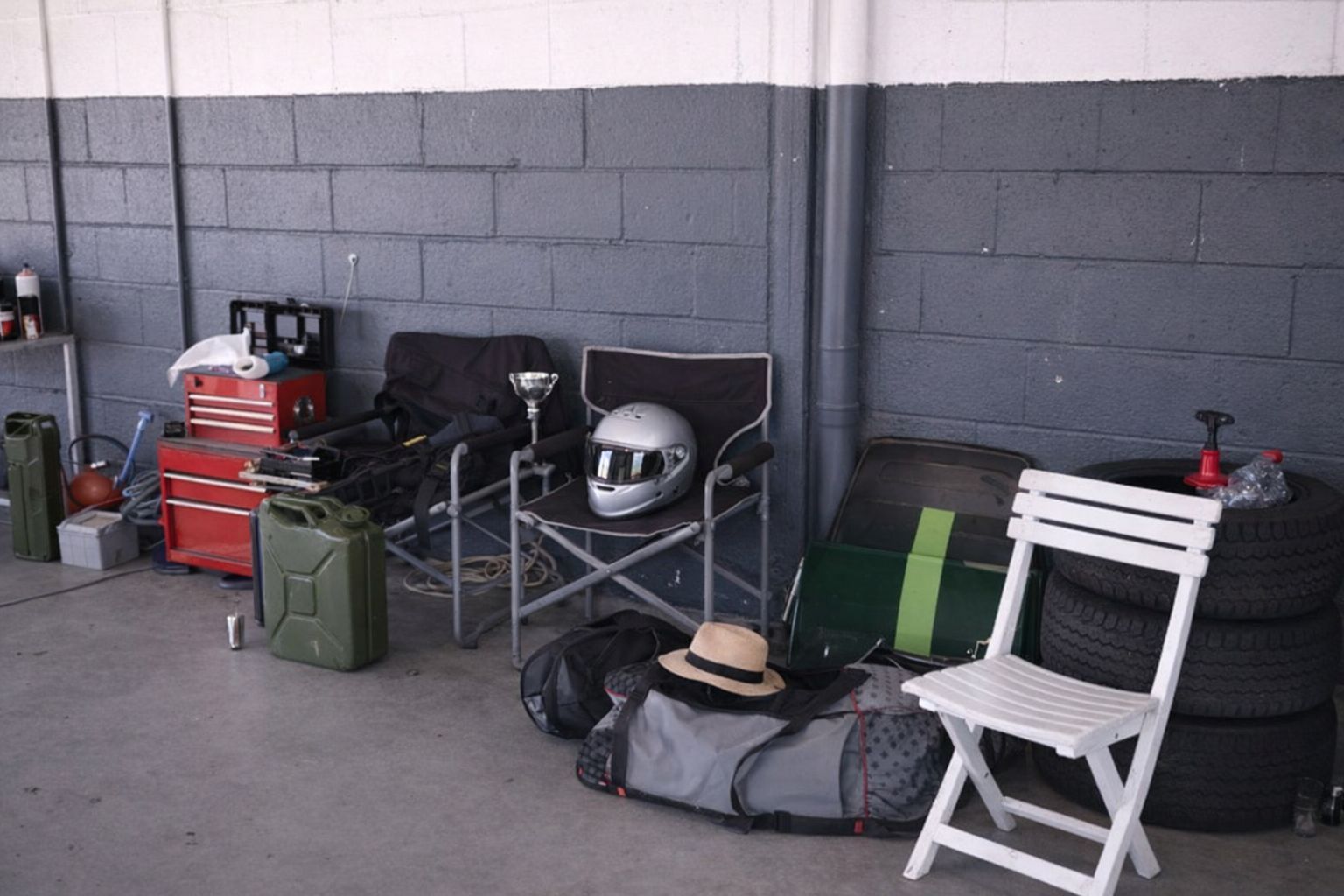 Träningsutrustning och motorsportstillbehör packade i ett garage för transport.