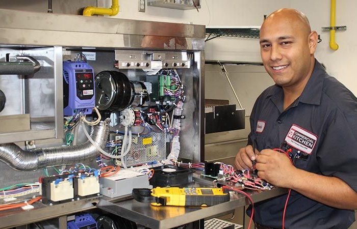Servicetekniker som reparerar elektronik i ett storkök.
