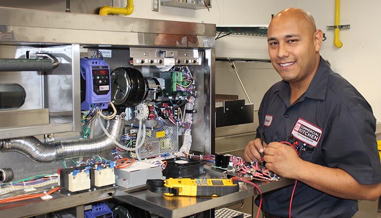 Servicetekniker som reparerar elektronik i ett storkök.