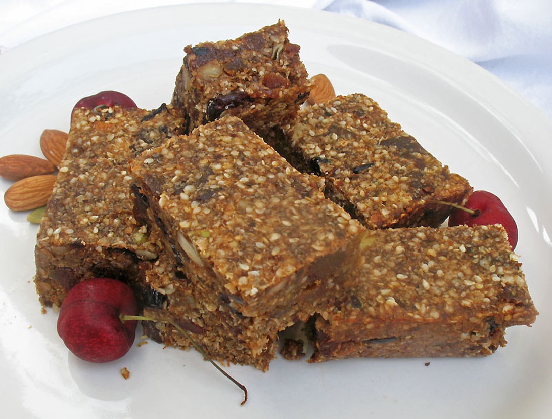 En vit tallrik med hemgjorda energibars gjorda på nötter, frön och torkad frukt.